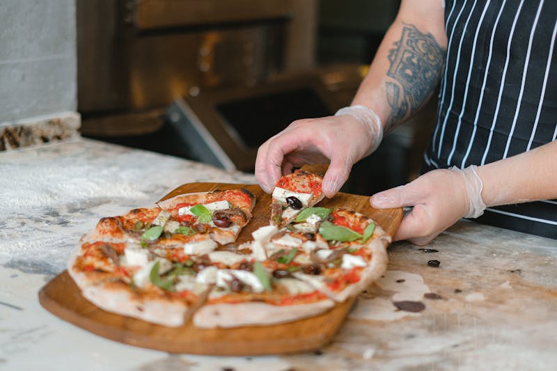 Custom modpizza being built with fresh toppings in the kitchen